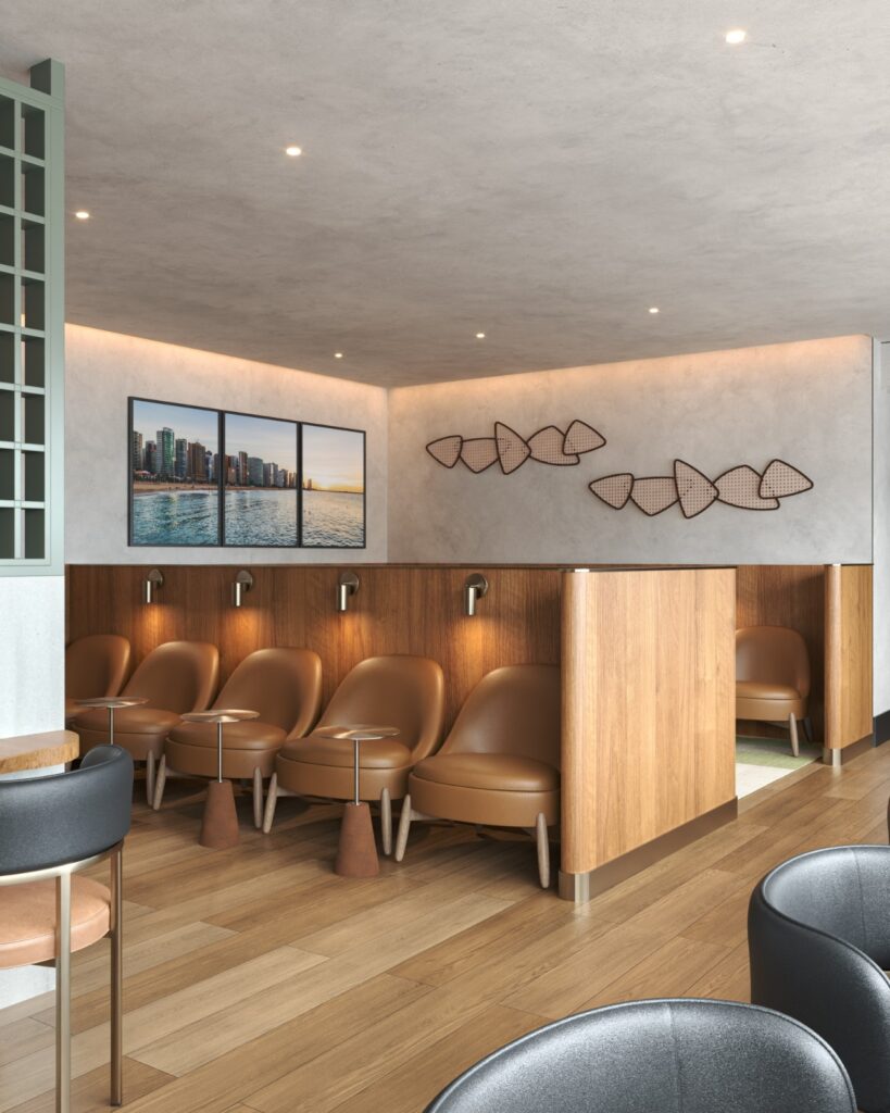 Lounge sofisticado com poltronas de couro marrom, divisórias em madeira, iluminação pontual e quadros decorativos com vista para o mar.